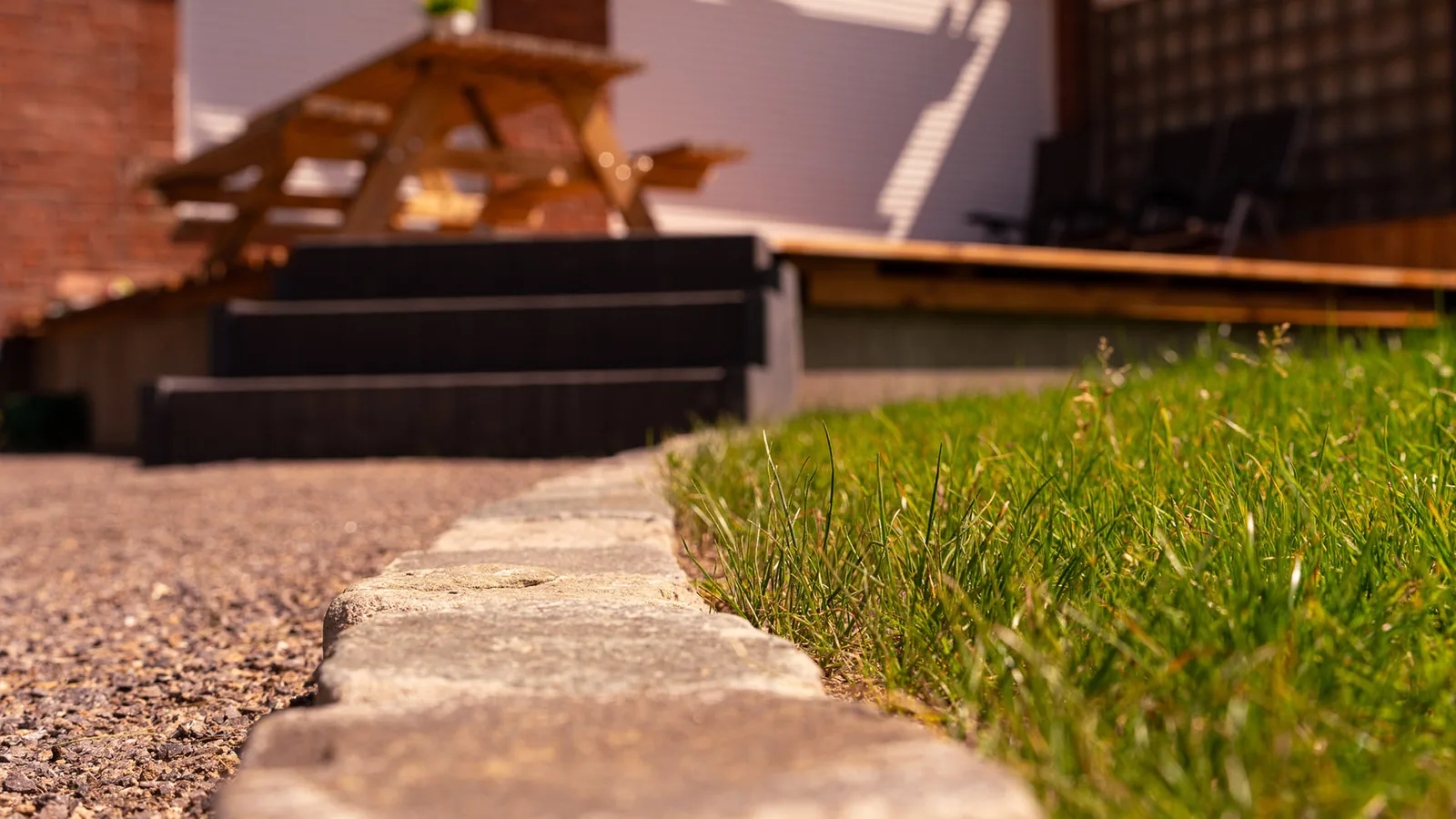 Gepflegter Rasenrand mit Natursteinkante und Gartenmöbeln